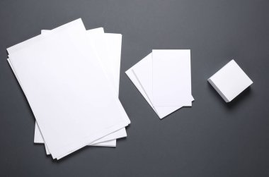 Koyu arkaplanda farklı şekil ve boyutlarda beyaz boş kağıtlar.