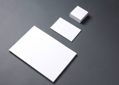Koyu arkaplanda farklı şekil ve boyutlarda beyaz boş kağıtlar.