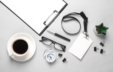 Boş bir kağıt, kimlik kartı ve gri arka planda ofis aksesuarları olan bir pano. İş konsepti. Tasarım şablonu. Üst Manzara. Düz yatıyordu