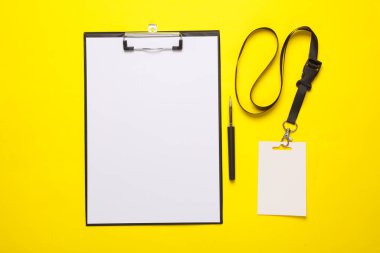 İçinde boş bir kağıt olan pano, ipte kimlik kartı, sarı arka plan. Tasarım şablonu. Üst Manzara. Düz yatıyordu