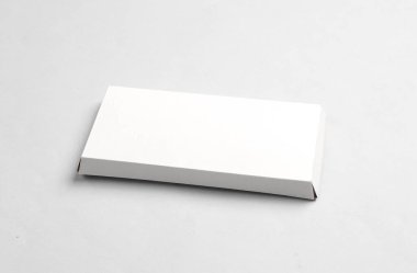 Gri arkaplanda çikolata çubuğu için beyaz karton kutunun bir kopyası