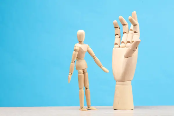 Wooden puppet and hand on a blue background