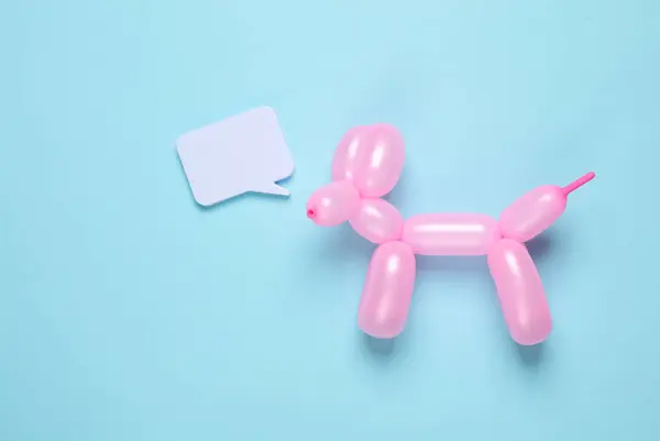 Pink balloon in the shape of dog with speech bubble on blue background. Top view