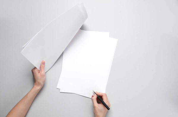 Женская рука с ручкой ставит подпись на листах бумаги или документа на сером фоне. Шаблон для дизайна. Контракт, концепция