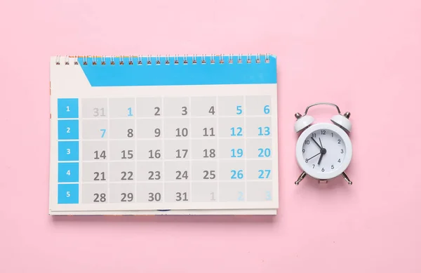 Alarm clock with calendar on pink background. Deadline, business concept