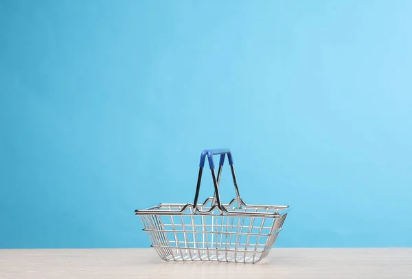 Miniature mini supermarket basket on the table, blue background