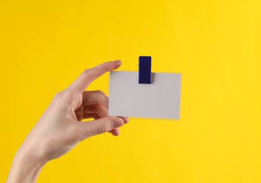 Elinde bir rozet var, sarı arka planda.