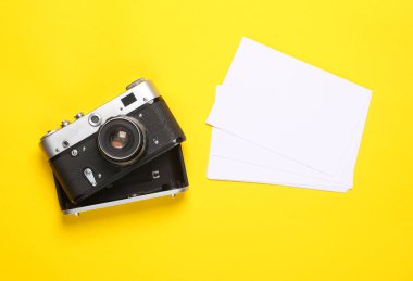 Sarı arka planda boş beyaz fotoğraflı Retro kamera. Yaratıcı düzen, modelleme, tasarım şablonu. Seyahat anıları