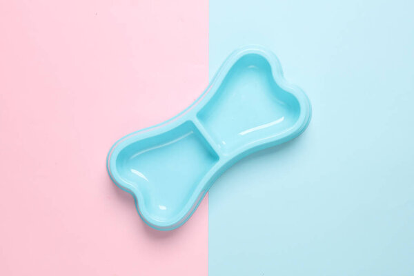 Dog bowl for food in the shape of a bone on a blue pink background