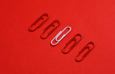 Kırmızı arka planda kırmızı ve beyaz ataçlar. Yaratıcı düzen. İş konsepti. Özellik, eşsizlik. Herkes gibi olma.