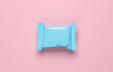 Pembe pastel arka planda mavi şeker paketi. Üst görünüm