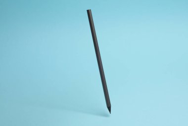 Mavi arka planda yükselen siyah kalem, gölgeli..