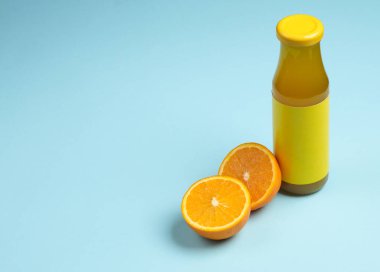 Mavi arka planda yarım portakal suyu olan bir şişe portakal suyu.
