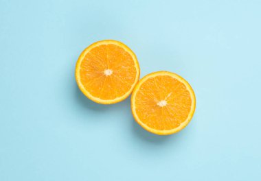 Mavi arka planda iki olgun arpelsin dilimi. Üst görünüm