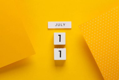 Sarı arka planda 11 Temmuz tarihli beyaz takvim küpleri. Yaratıcı yerleşim