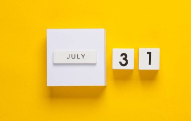 Sarı arka planda tarih 31 Temmuz olan beyaz takvim küpleri. Yaratıcı yerleşim