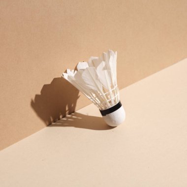 Bej arka planda gölgeli Badminton mekik siki. Minimalist fotoğraf. Yaratıcı yerleşim