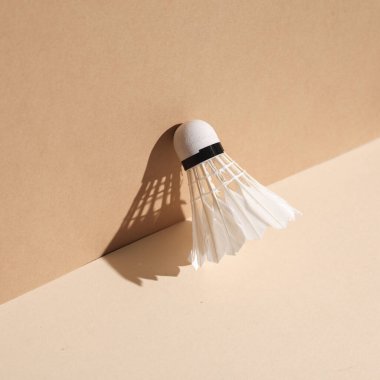 Bej arka planda gölgeli Badminton mekik siki. Minimalist fotoğraf. Yaratıcı yerleşim