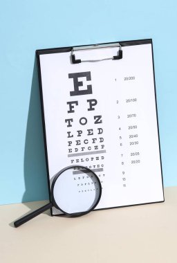 Mavi bej arka planda büyüteç ve göz testi çizelgesi. Görüş sınavı