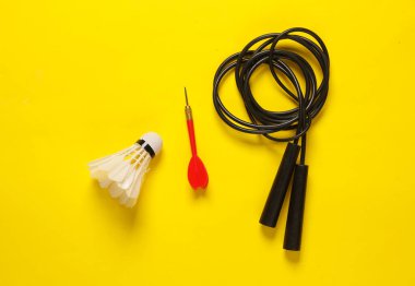 Spor ve açık hava aktiviteleri. Shuttlecock, ip atlama ve sarı arka planda dart.