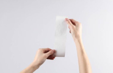 Kadınların elleri gri arka planda beyaz, boş bir alışveriş makbuzu tutuyor. Tasarım şablonu. Metin için yerler