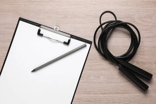Workout plan. Clipboard with jump rope on the table. Healthy lifestyle, weight loss