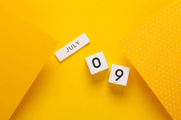 White calendar cubes with date july 09 on yellow background. Creative layout