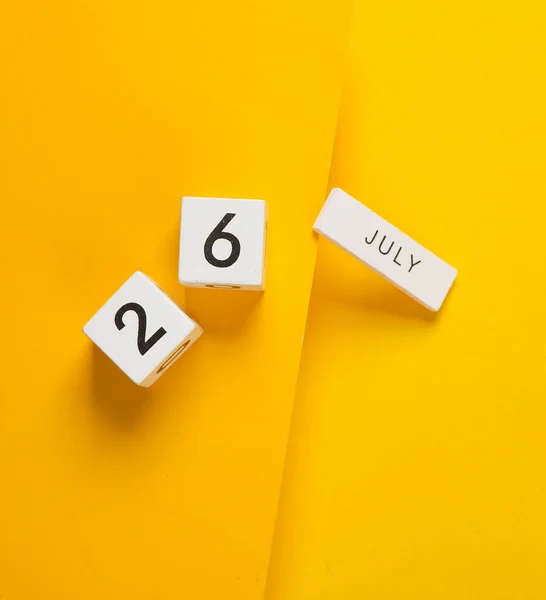 White calendar cubes with date july 26 on yellow background. Creative layout