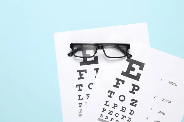 Eyeglasses with eye test charts on blue background. Vision examination