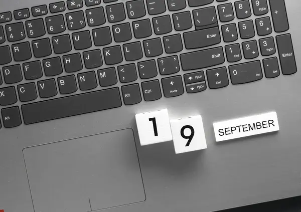 White wooden block calendar with date september 19 on laptop keyboard. Business, deadline, planning