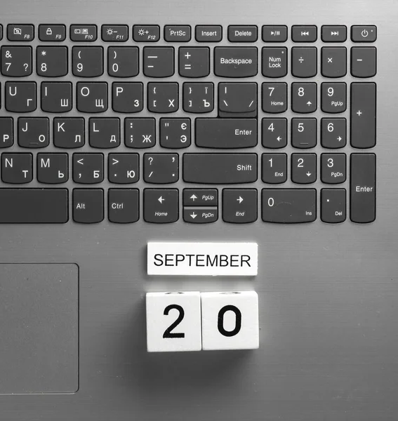 White wooden block calendar with date september 20 on laptop keyboard. Business, deadline, planning