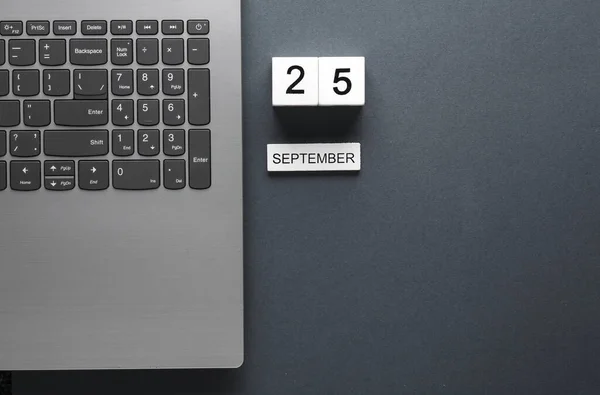 White wooden block calendar with date september 25 and laptop on gray background. Business, deadline, planning