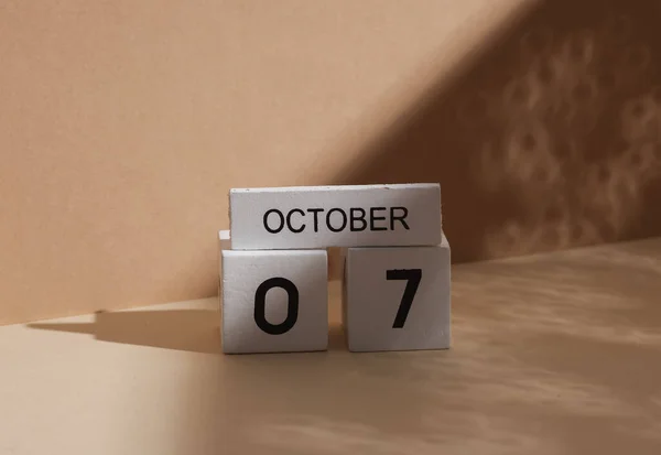 Wooden white block calendar with date october 07 on beige background with shadow. Creative layout, planning, holiday