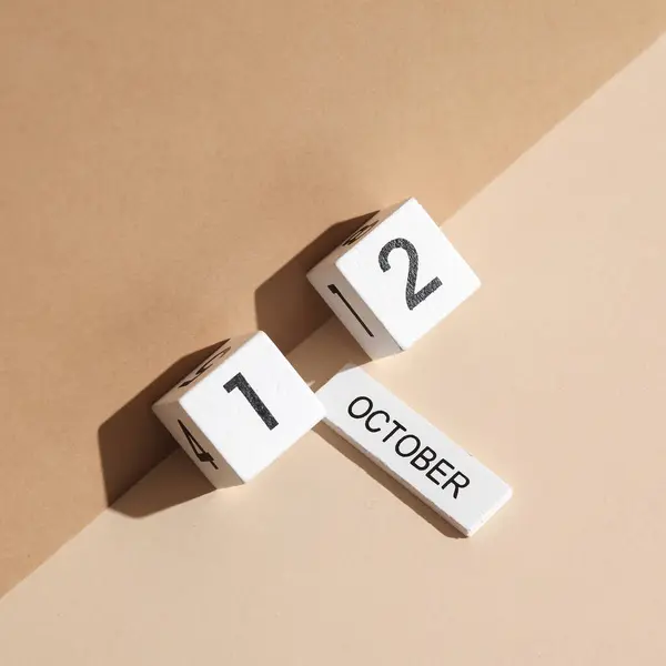 Wooden white block calendar with date october 12 on beige background with shadow. Creative layout, planning, holiday
