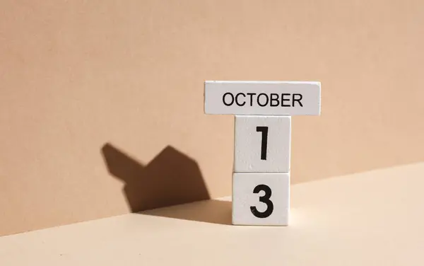 Wooden white block calendar with date october 13 on beige background with shadow. Creative layout, planning, holiday
