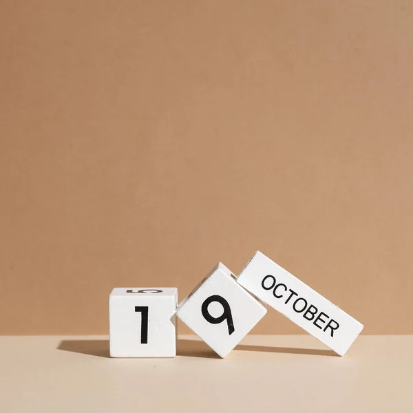 Wooden white block calendar with date october 19 on beige background with shadow. Creative layout, planning, holiday