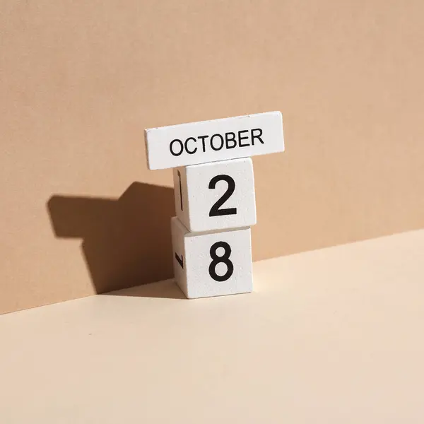 Wooden white block calendar with date october 28 on beige background with shadow. Creative layout, planning, holiday