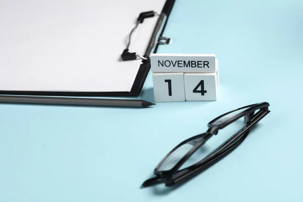 Business concept, deadline. Calendar with the date november 14 and stationery, office supplies on a blue background.