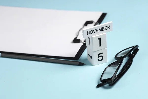 Business concept, deadline. Calendar with the date november 15 and stationery, office supplies on a blue background.