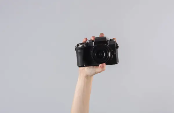 stock image Woman's hand holding a modern digital camera on gray background