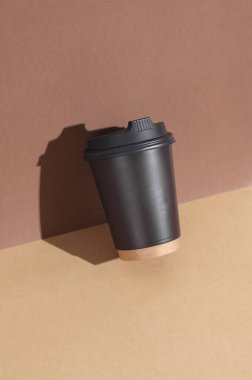 Kahverengi arka planda, gölgeli tek kullanımlık karton bardak. Yaratıcı yerleşim