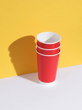 Kırmızı boş bardaklar sarı-beyaz arka planda ve gölgeli