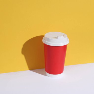 Sarı-beyaz arka planda tek kullanımlık kırmızı bardak.