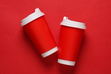 Kırmızı arka planda sıcak içecekler için kapaklı kırmızı kullan-at bardakların maketi