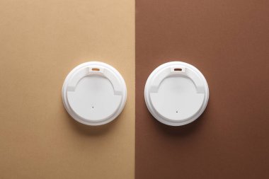 Kahverengi bej arka planda beyaz plastik tek kullanımlık kapaklar. Model, tasarım şablonu