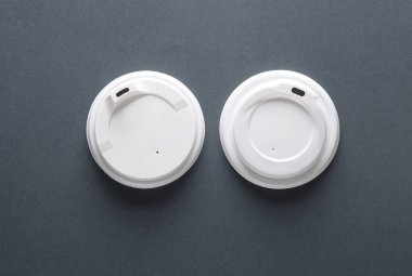 Koyu gri arka planda tek kullanımlık beyaz plastik kapaklar. Model, tasarım şablonu