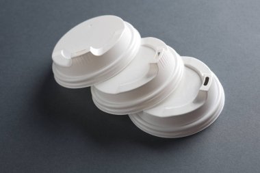 Koyu gri arka planda tek kullanımlık beyaz plastik kapaklar. Model, tasarım şablonu