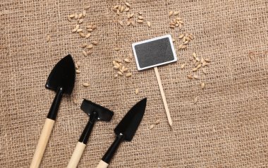 Çuval bezinde yazı tahtası olan bir grup minyatür bahçe aletleri.