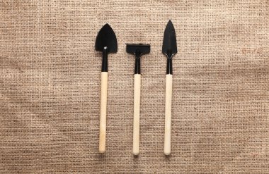 Çuval bezi üzerinde minyatür bahçe aletleri (tırmıklar, kürekler) seti