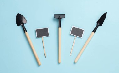 Ev bitkisi (tırmık, kürek) ve mavi arka planda karatahta için bahçe aletleri. Üst görünüm 